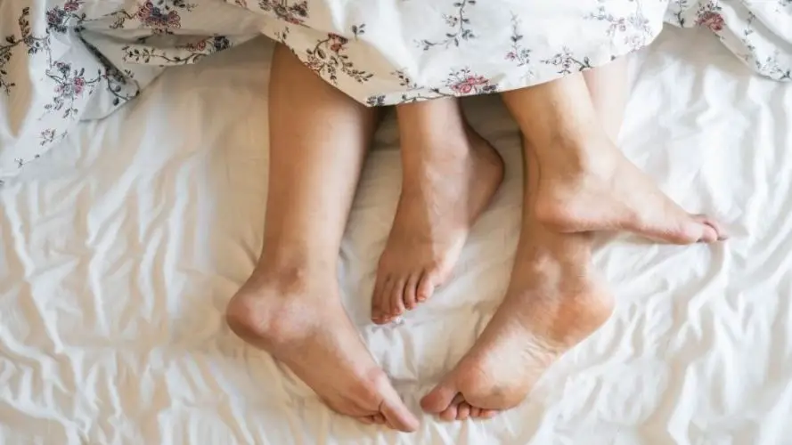 The feet of a couple in bed