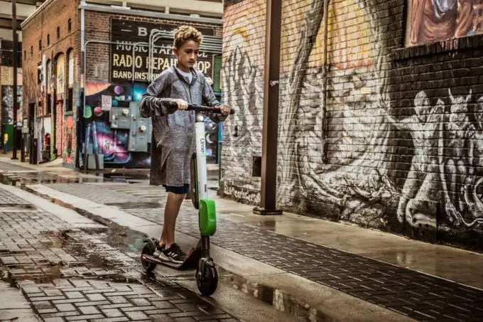 A young boy rides an electric scooter through an urban street.