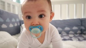 Photo of a crawling baby with a pacifier